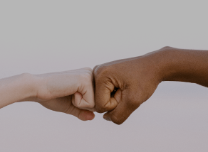 
                Two hands of different ethnicities bumping fists to represent Laurastar’s commitment to equality and diversity at work.
                